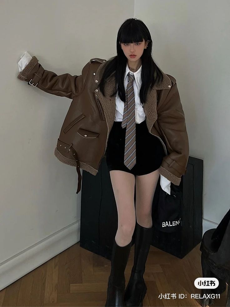 Woman in a brown aviator jacket, white shirt, and black shorts with a striped tie