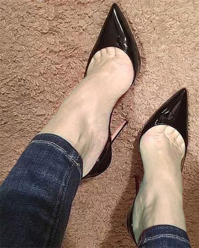 Person wearing black pointed-toe high heels and jeans on a brown carpet
