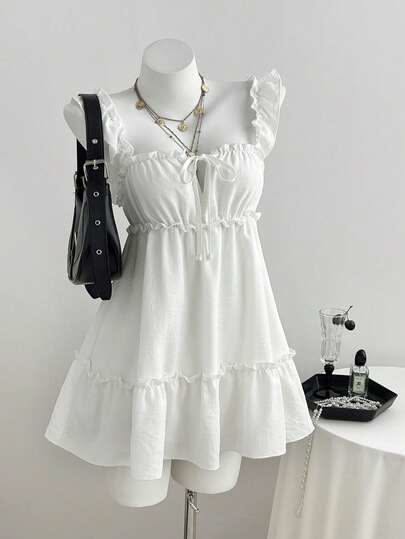 White ruffle strap dress on a mannequin with a black handbag and layered necklaces