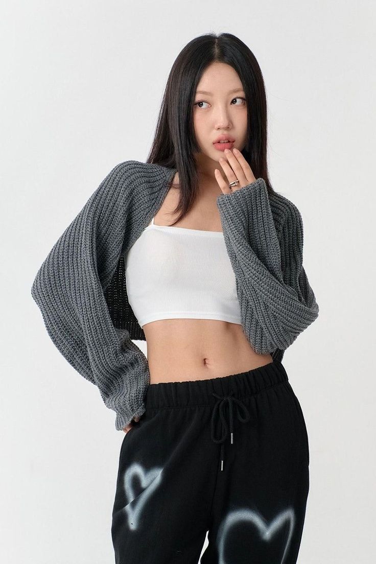 Woman in a white crop top and grey cardigan with black sweatpants