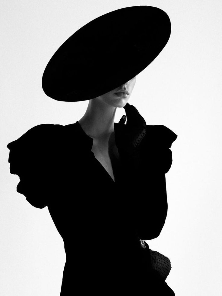 Woman in a wide brim hat and gloves in a dramatic black and white portrait