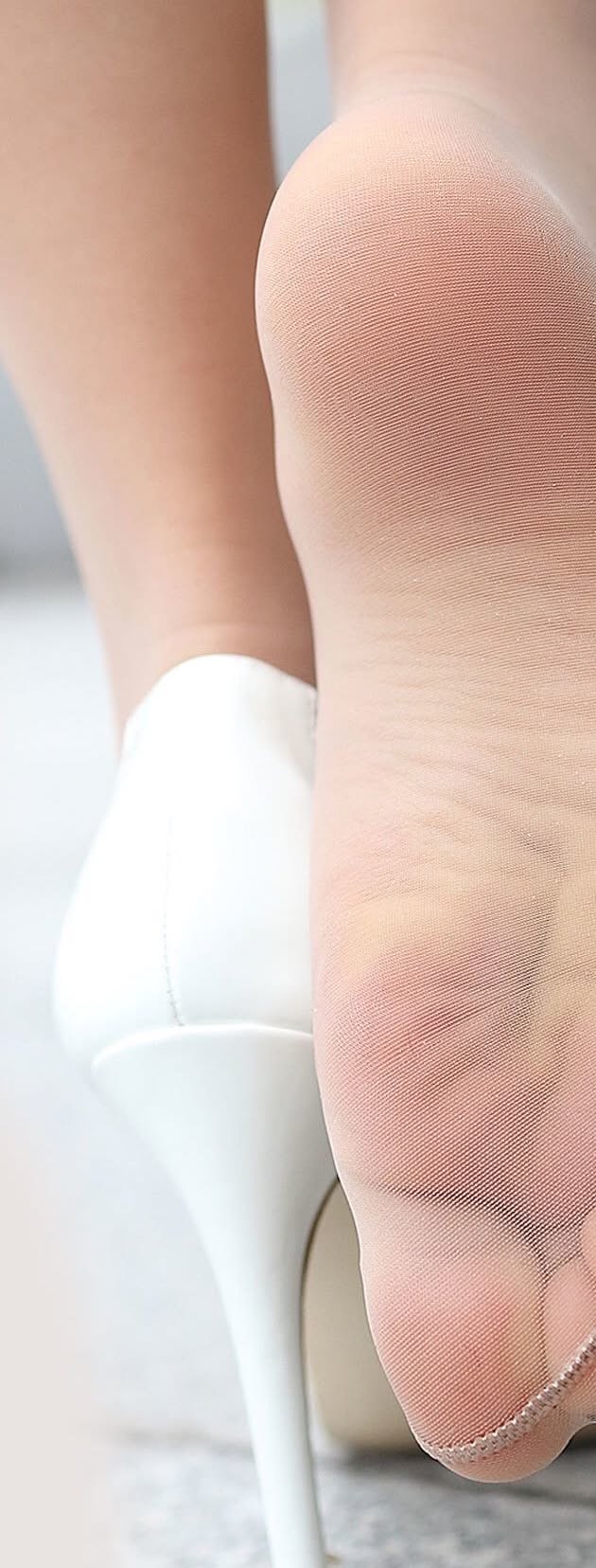 Close up of a foot in nylon stockings and white high heels