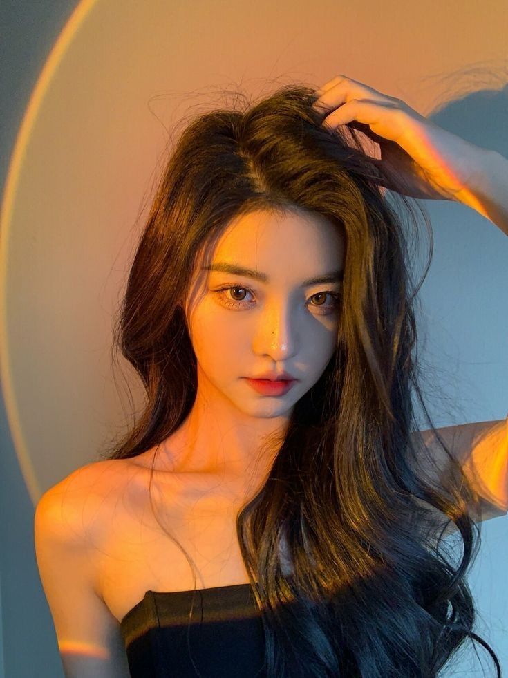 Woman with long black hair in a strapless top with warm dramatic lighting