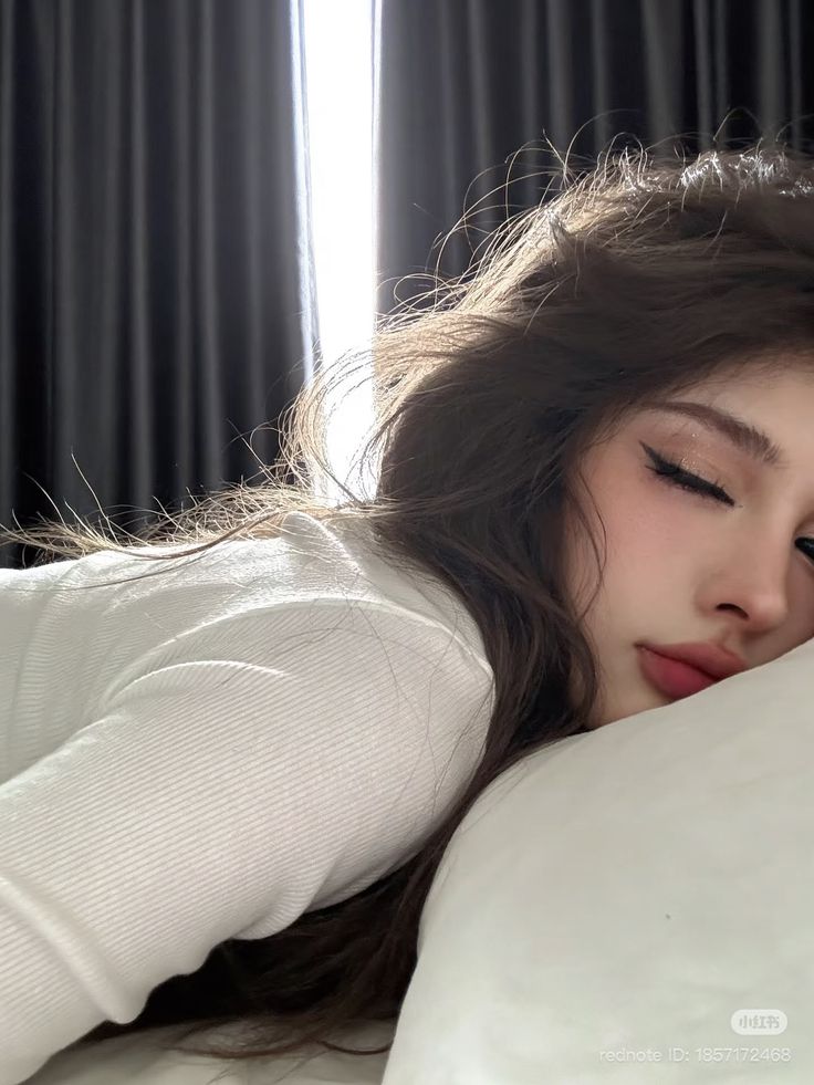 Woman with long hair and closed eyes lying on a pillow with backlight