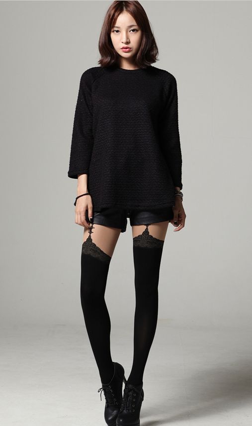 Woman in a black top, shorts, and thigh-high stockings with lace trim