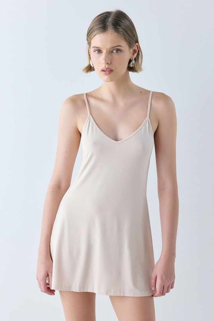 Woman in a light-colored slip dress with short blonde hair and hoop earrings