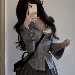 Person with long dark hair taking a mirror selfie in a striped shirt and pleated skirt