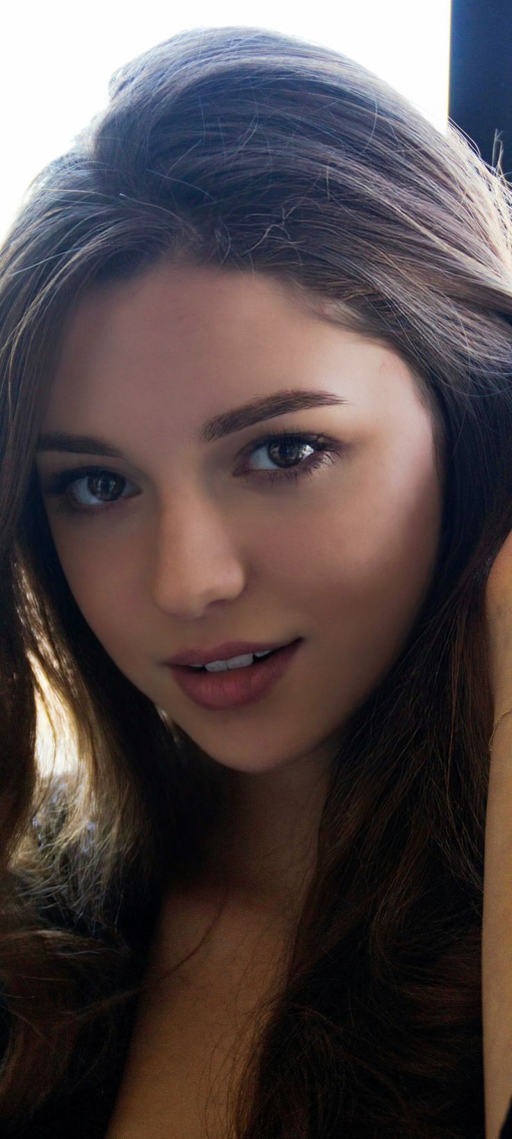 Close up portrait of a young woman with long brown hair and soft lighting