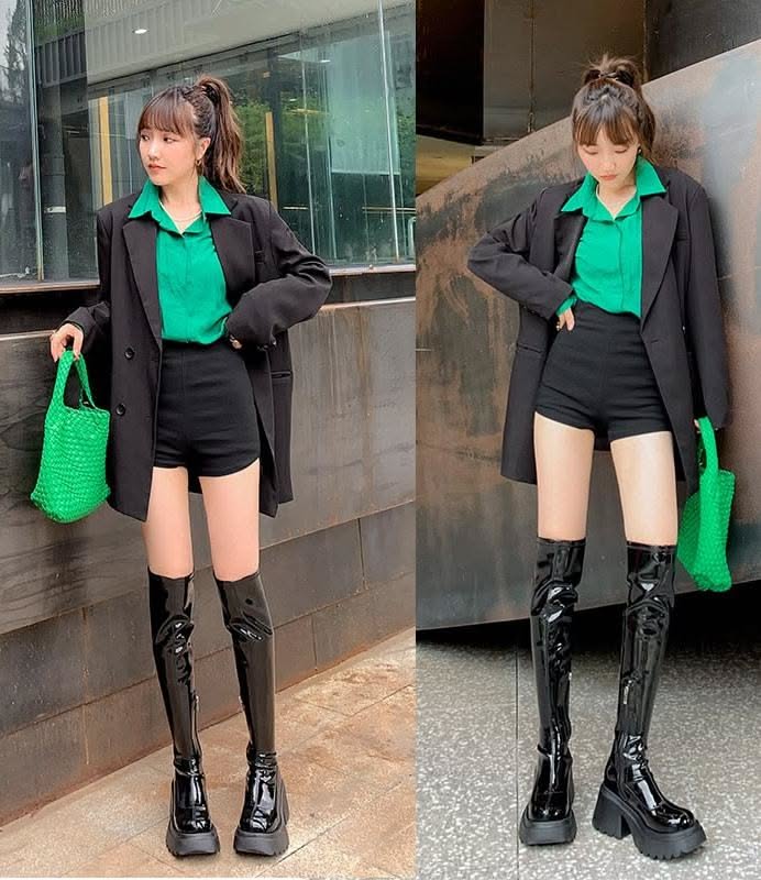 Woman in a black blazer, green shirt, black shorts, and thigh high boots outdoors
