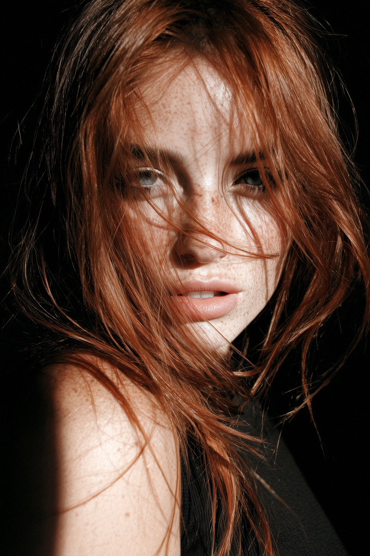 Woman with red hair and freckles in dramatic lighting