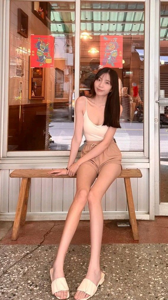 Woman with long dark hair sitting on a wooden bench outdoors