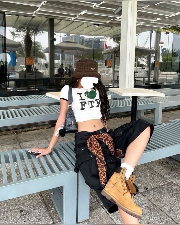 Woman in a crop top and cargo pants with a leopard print scarf, sitting outdoors