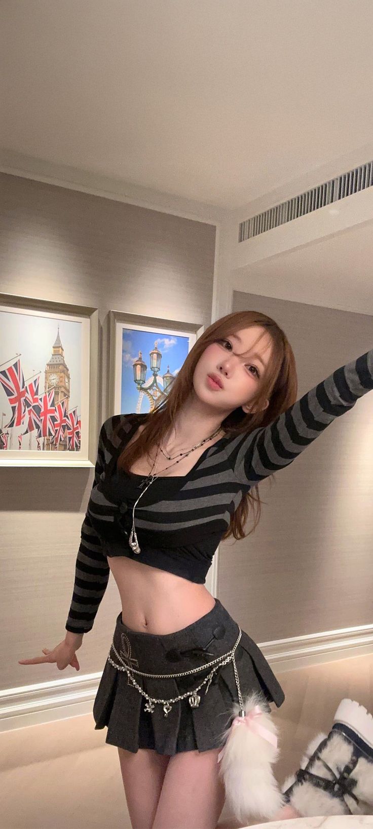 Woman in a striped top and mini skirt with exposed midriff posing indoors