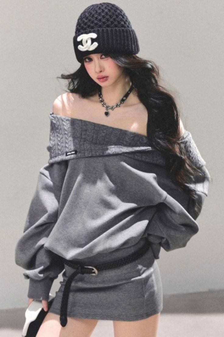 Woman in a gray off-shoulder top and beanie with long dark hair