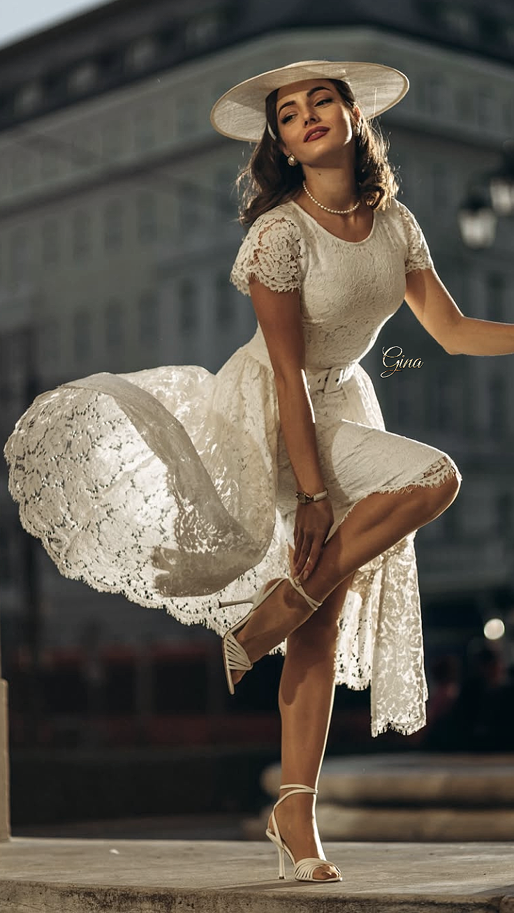Woman in a white lace dress and hat posing outdoors