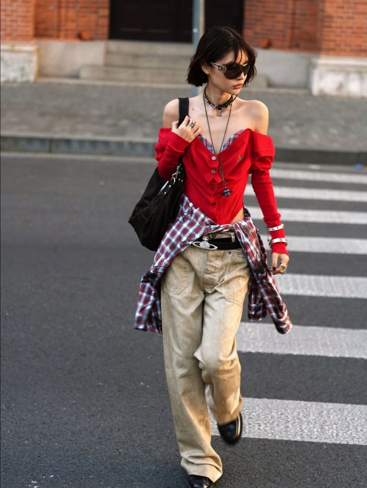 Person in an off-shoulder red top and baggy pants walking on a street