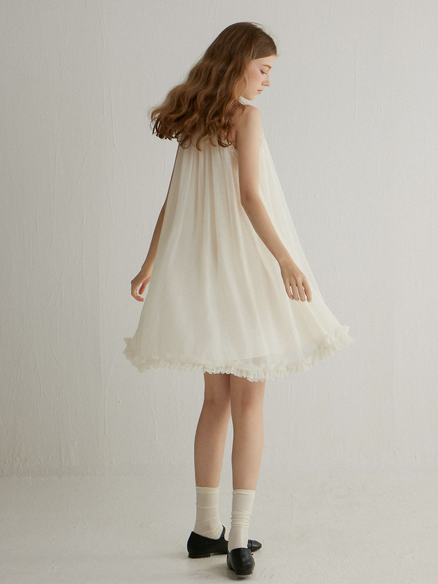 Woman in a white dress with ruffle trim and white socks indoors
