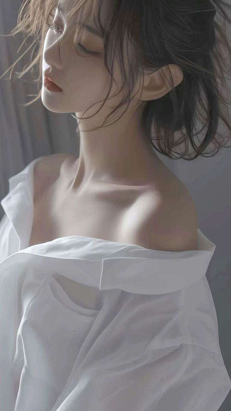 Woman with messy hair and red lips wearing an off-shoulder white shirt