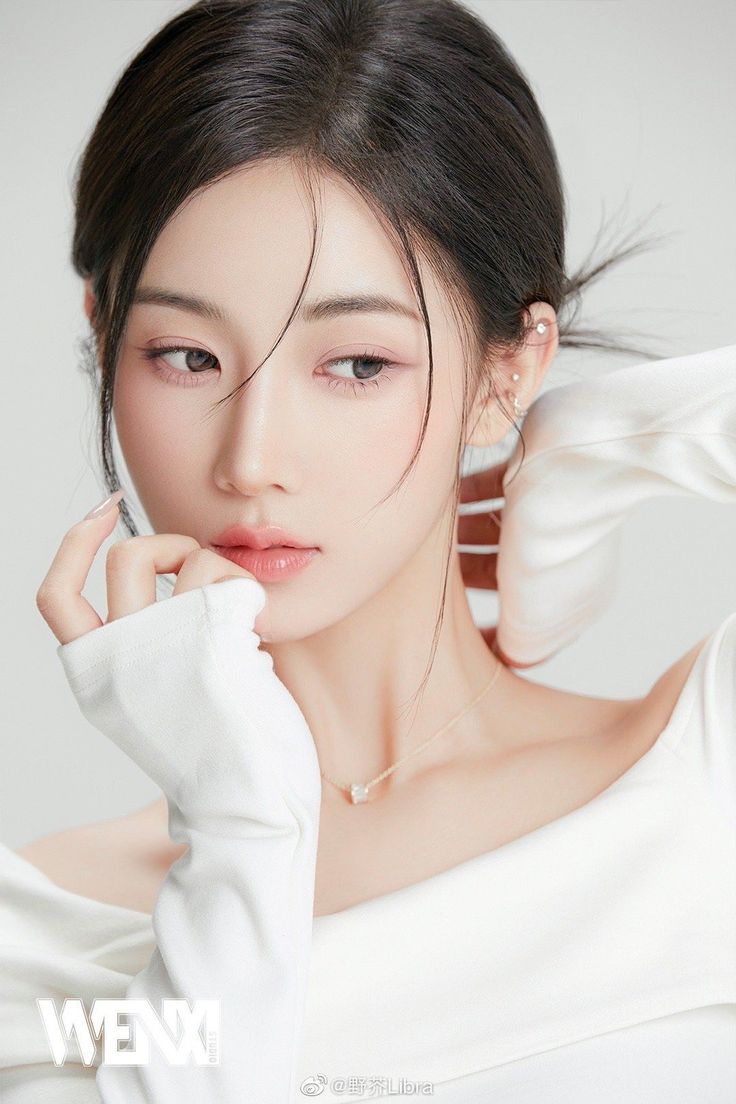 Woman with black hair in an updo wearing a white top and necklace
