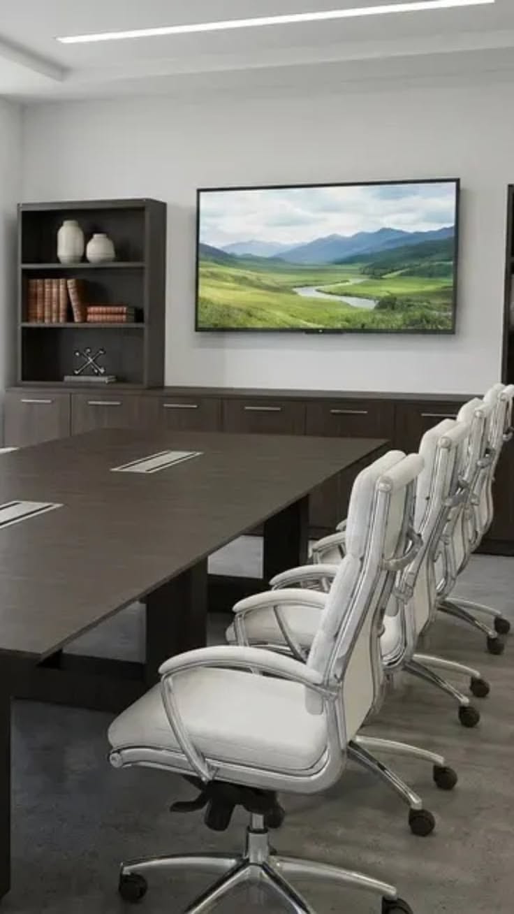 Modern conference room with a long table, white chairs, and a flat screen TV