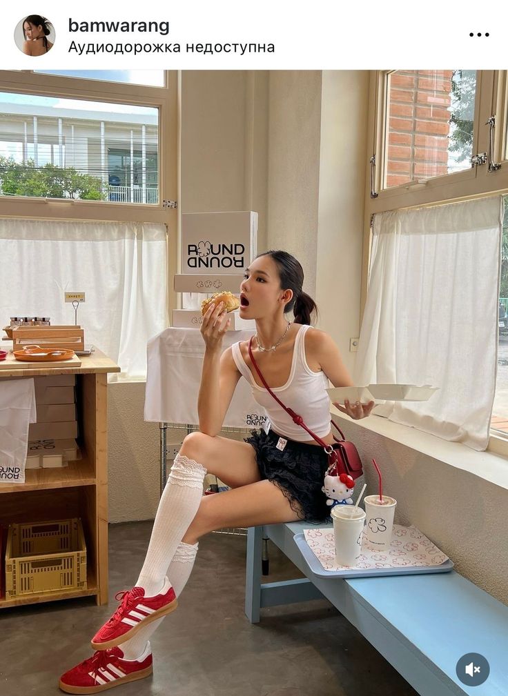 Woman in a white tank top and black mini skirt eating in a cafe