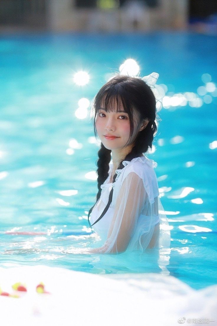 Woman with twin tails in a white sheer dress in a swimming pool