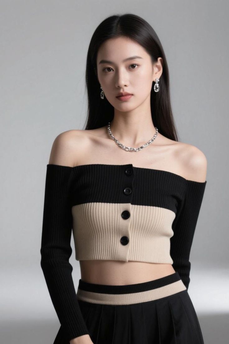 Woman with long black hair wearing an off-shoulder crop top and jewelry in a studio