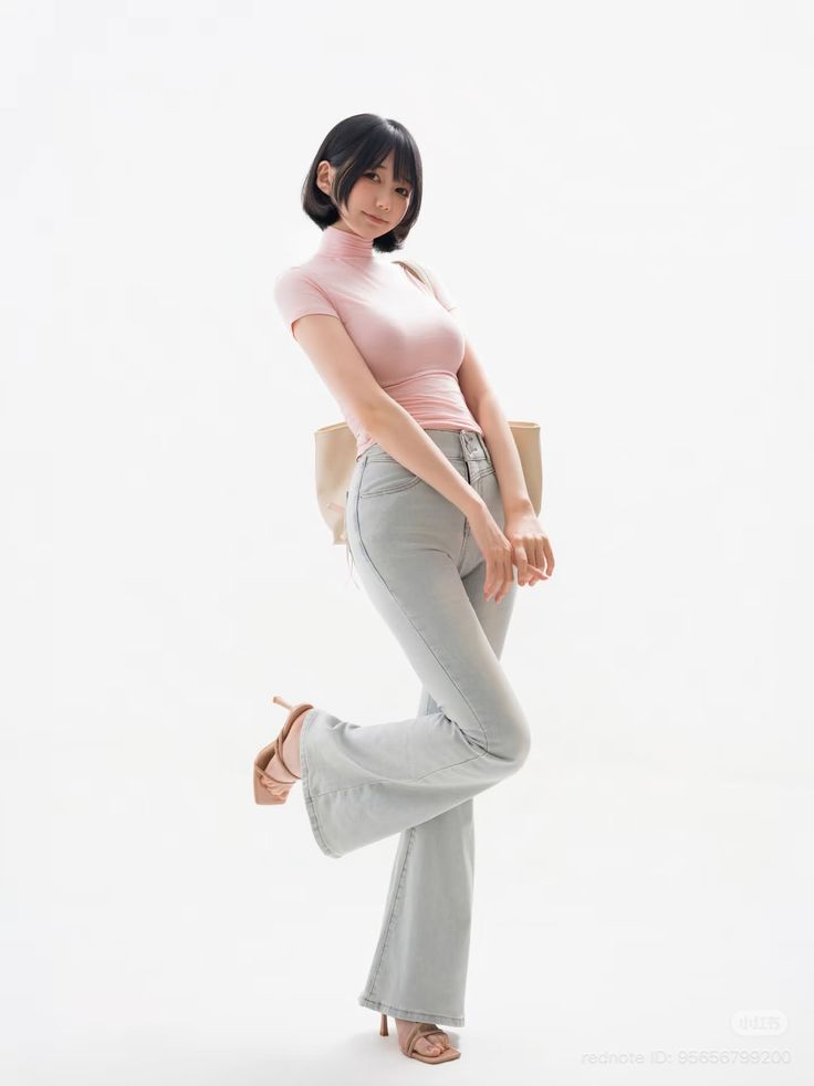 Woman with short black hair in a pink top and flared jeans posing on white background