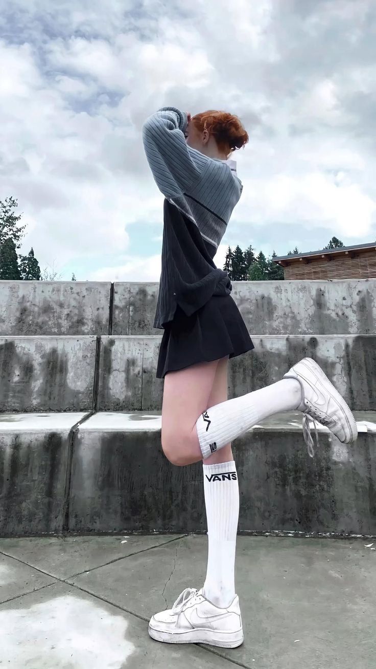 Person with red hair in a mini skirt and long socks posing outdoors