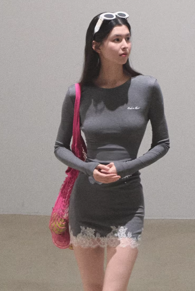 Woman in a gray dress with white lace trim and a pink mesh bag