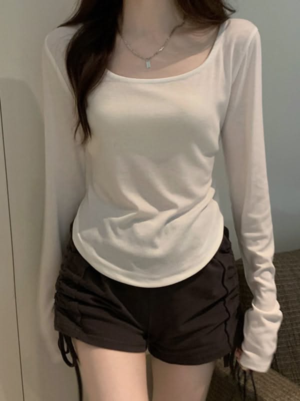 Person in a white long sleeve shirt and black shorts with a silver necklace