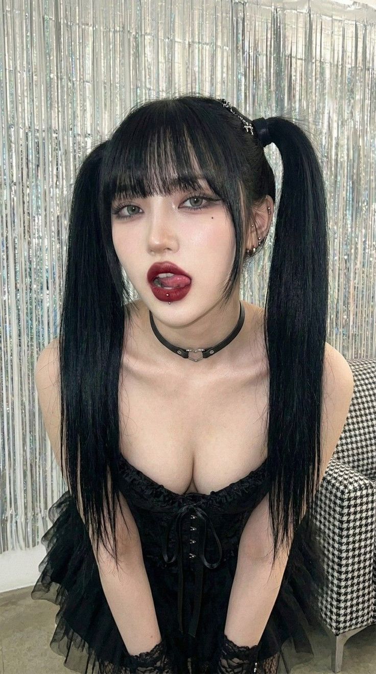 Woman with black twin tails and dark lipstick in a gothic-style outfit