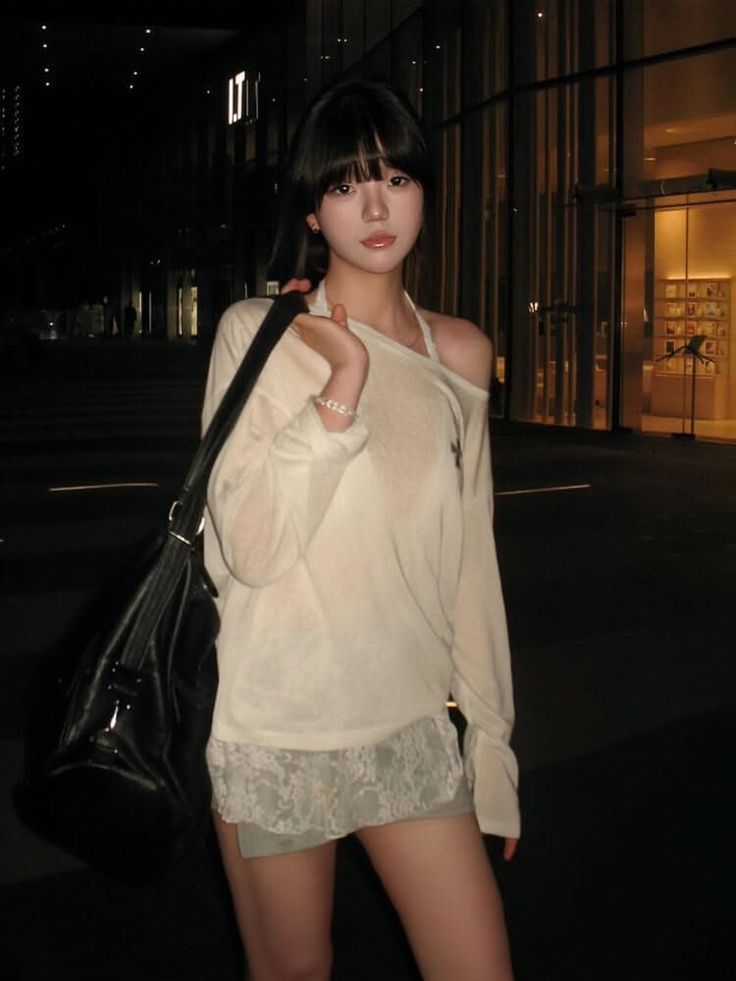 Woman with short bangs and an off-shoulder top with a lace-trimmed mini skirt at night
