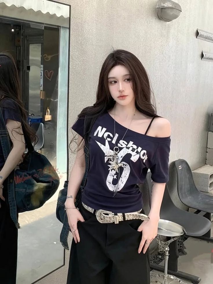 Woman with long dark hair wearing an off-shoulder top and black pants outdoors