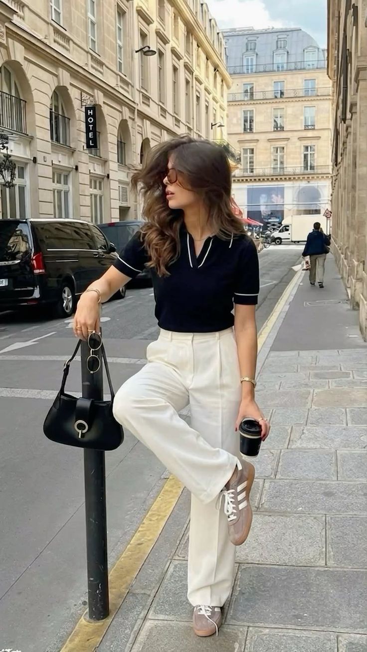 Woman in a black polo shirt and white pants posing on a city street