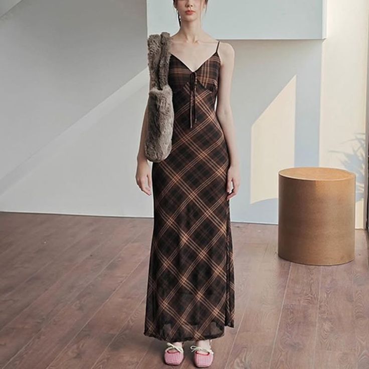 Woman in a plaid maxi dress with a furry bag and pink shoes indoors