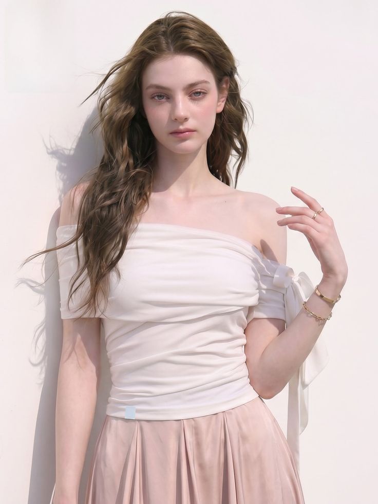 Woman with long hair wearing an off-shoulder top and pleated skirt outdoors