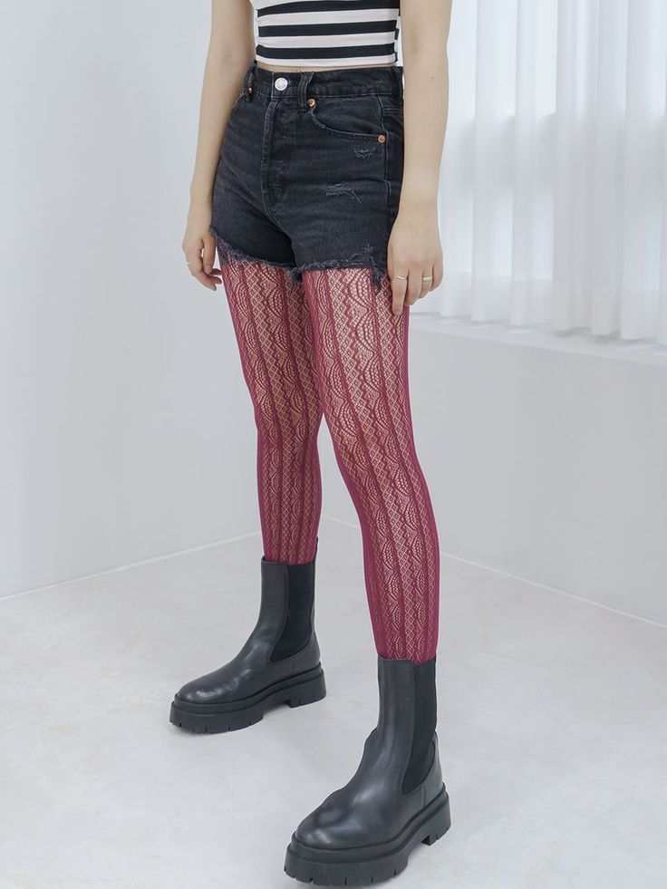 Person wearing red patterned tights, denim shorts, and a striped crop top indoors