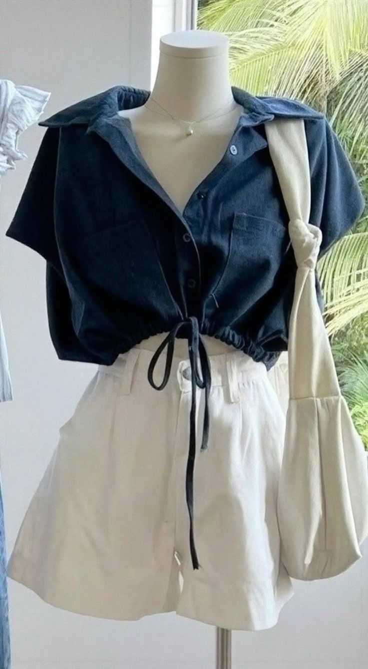 Mannequin wearing a dark blue cropped shirt and white shorts with a shoulder bag