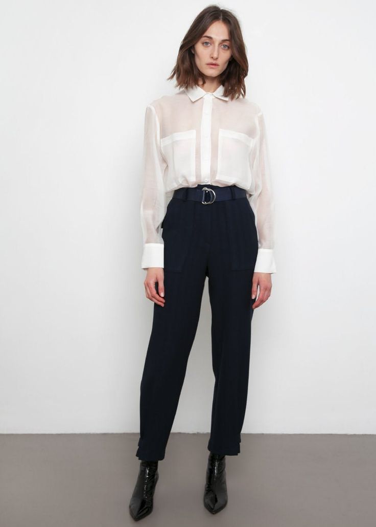 Woman in a sheer white shirt and dark pants with black boots