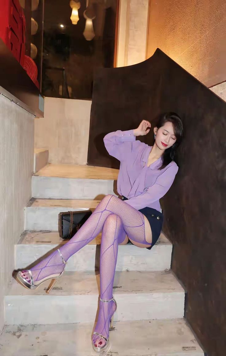 Woman in purple fishnet stockings and high heels sitting on stairs