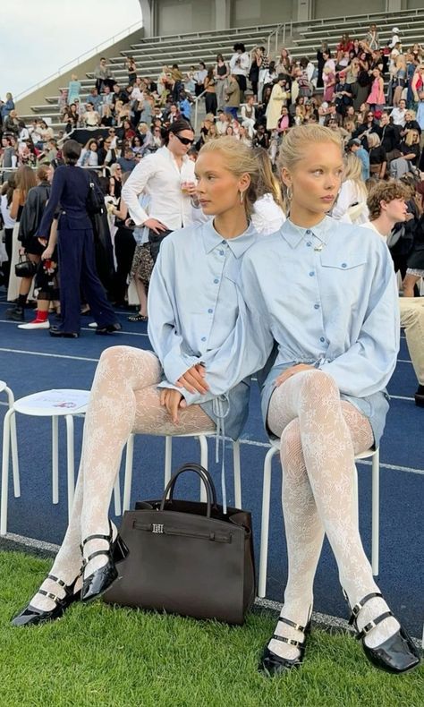 Two women in matching outfits sitting on chairs at an outdoor event