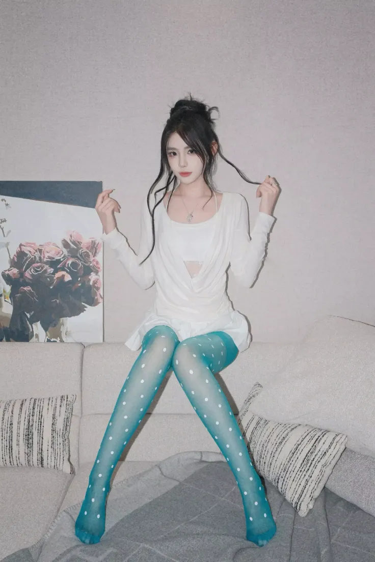 Woman in a white top and blue polka dot tights sitting on a couch