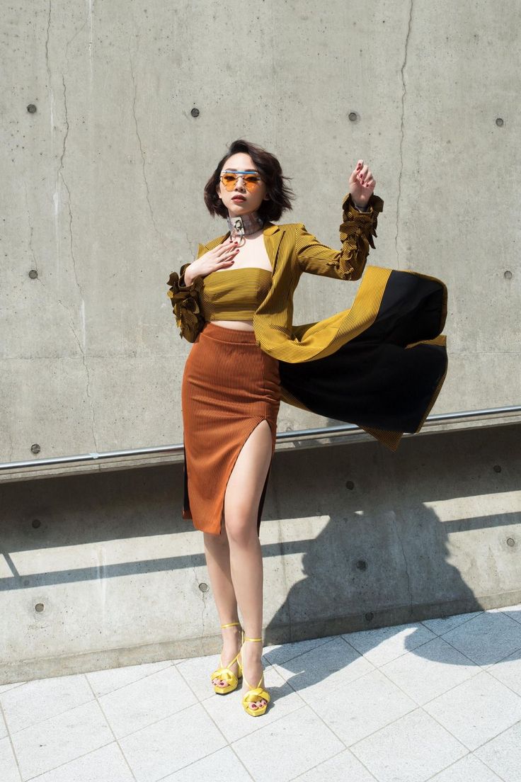 Woman in a crop top and high-slit midi skirt with a long jacket and sunglasses