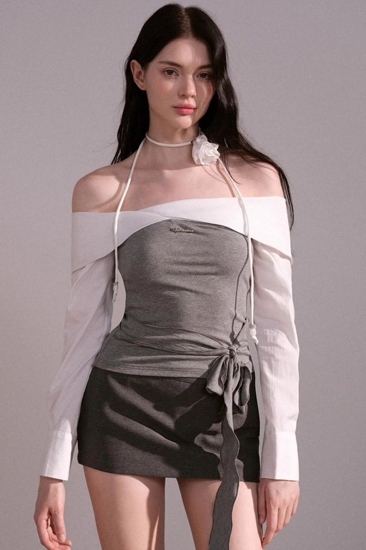 Woman with long dark hair wearing an off-shoulder top and mini skirt