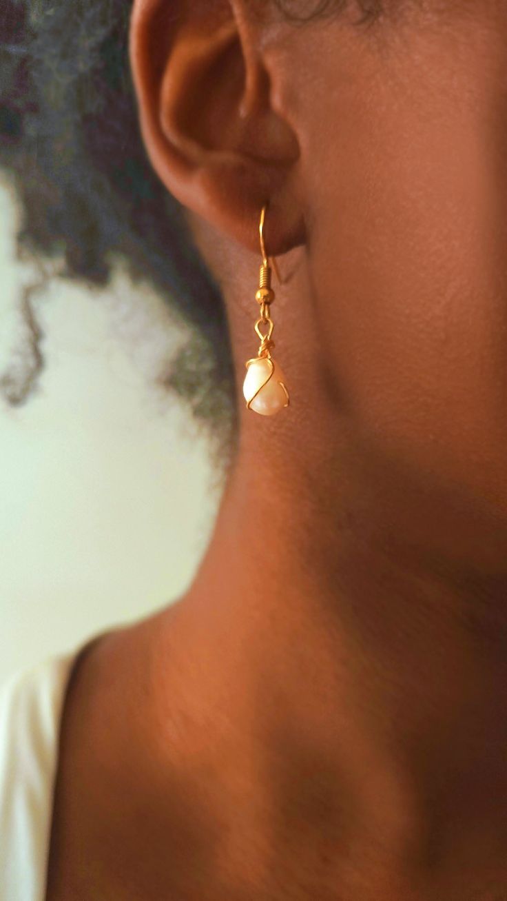 Close up of a person's ear with a pearl and gold wire earring