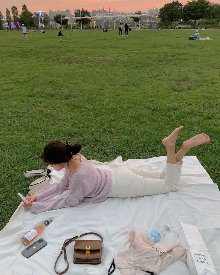 Woman lying on a picnic blanket in a park at sunset