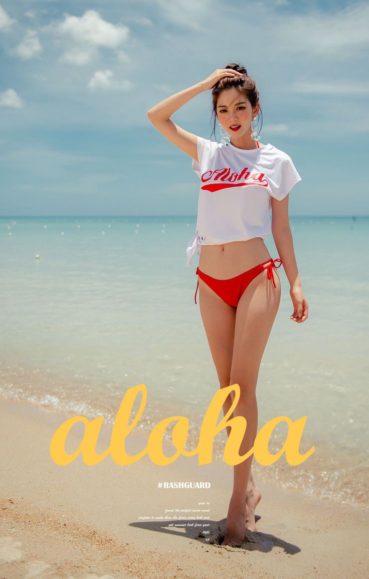 Woman in a red bikini and white crop top posing on a sandy beach