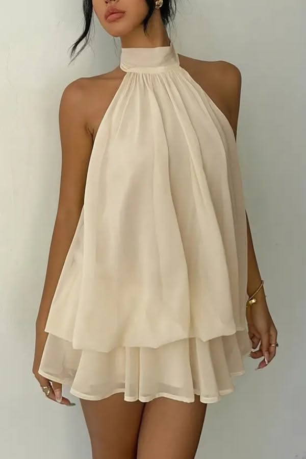 Woman in a cream-colored halter mini dress with gold jewelry