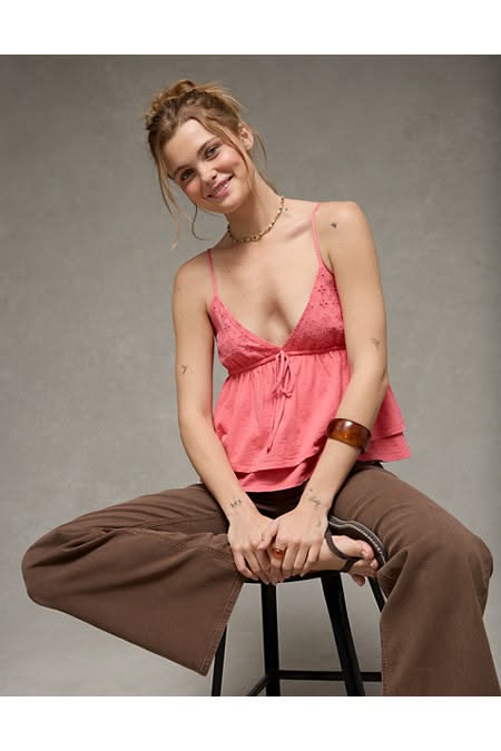 Woman in a pink top and brown pants sitting on a stool indoors